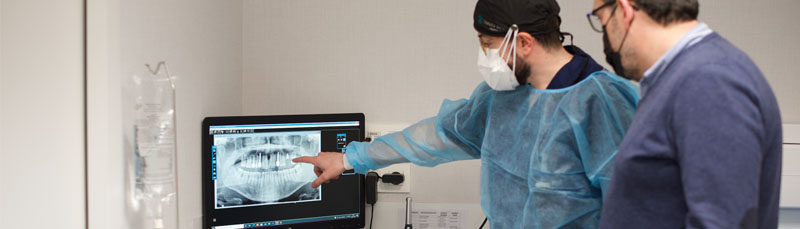 Odontólogo señala el resultado de la pantomografía a un paciente